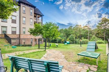 A green bench sits in a grassy area in front of a building.